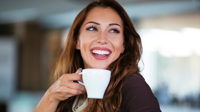 Uśmiechnięta kobieta pije kawę