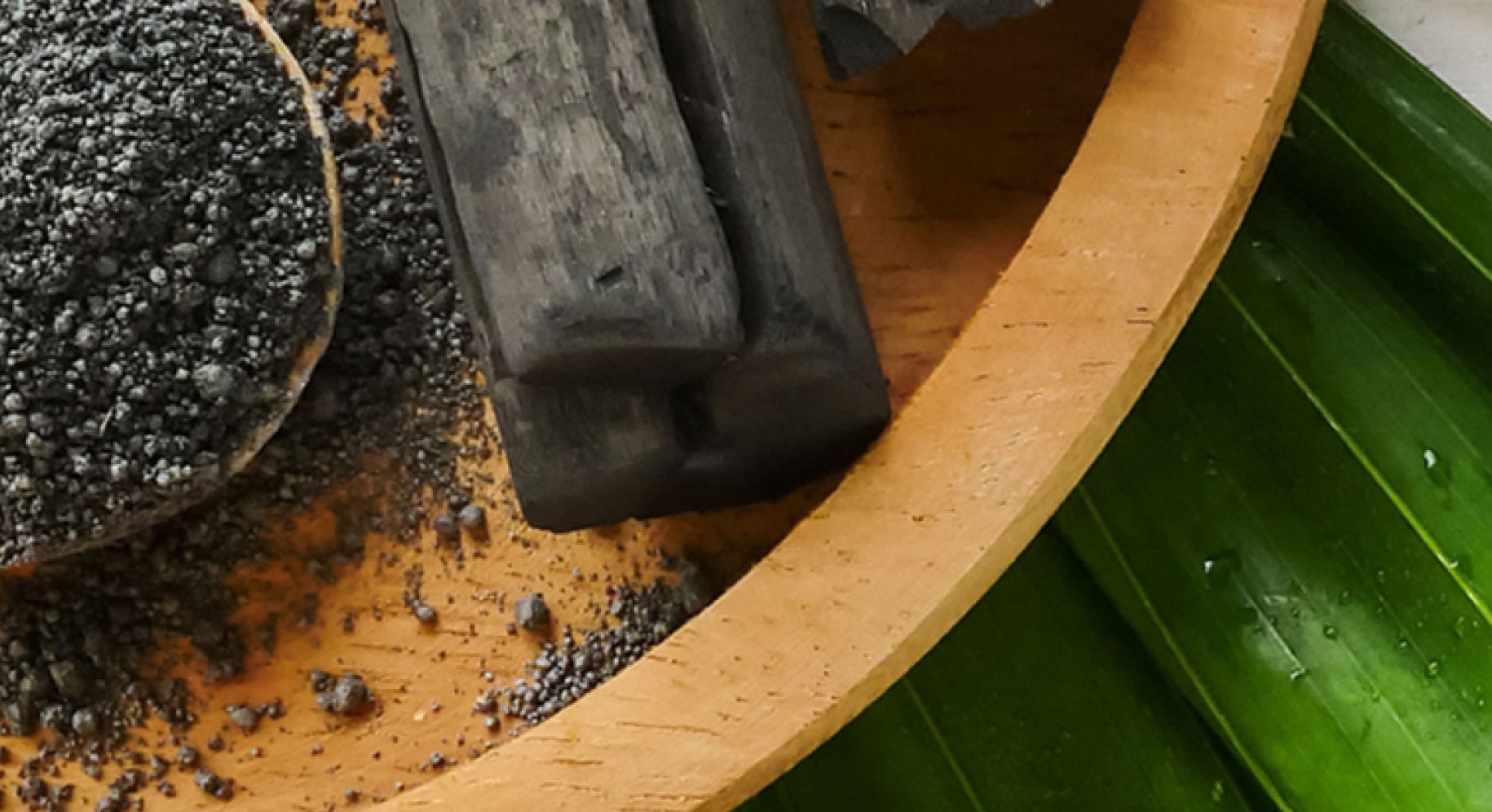 Kawałki węgla aktywnego na bambusowym talerzu z liśćmi.