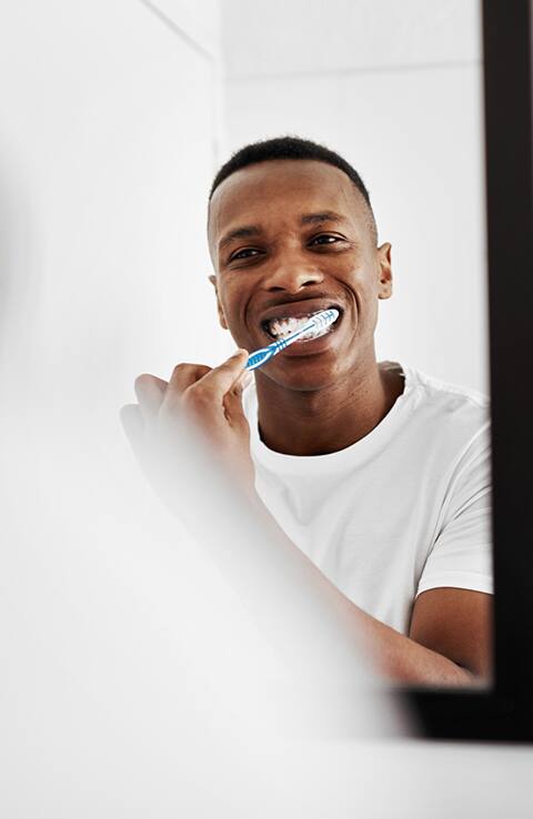 hombre cepillando sus dientes frente al espejo hombre cepillando sus dientes frente al espejo
