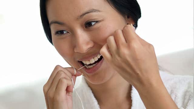 Kobieta czyści zęby nitką