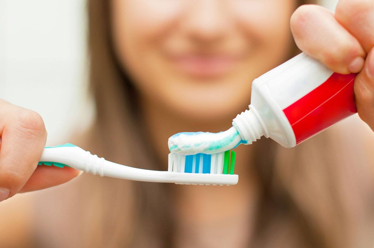 zbliżenie kobiety wyciskającej pastę do zębów na szczoteczkę do zębów