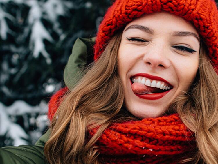 Uśmiechnięta kobieta na zewnątrz w zimowej scenerii.