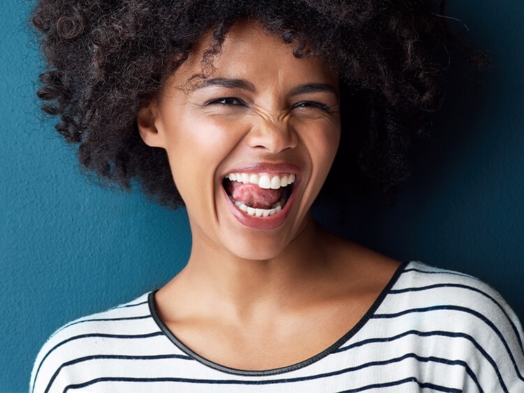 Uśmiechnięta czarnoskórą kobietą z językiem na górnych zębach