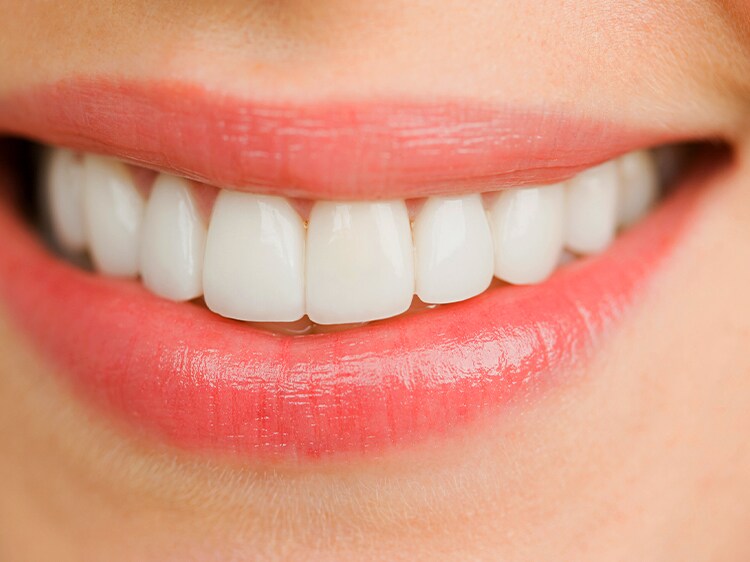 Zbliżenie na uśmiechniętą twarz pokazującą czyste, białe zęby.
