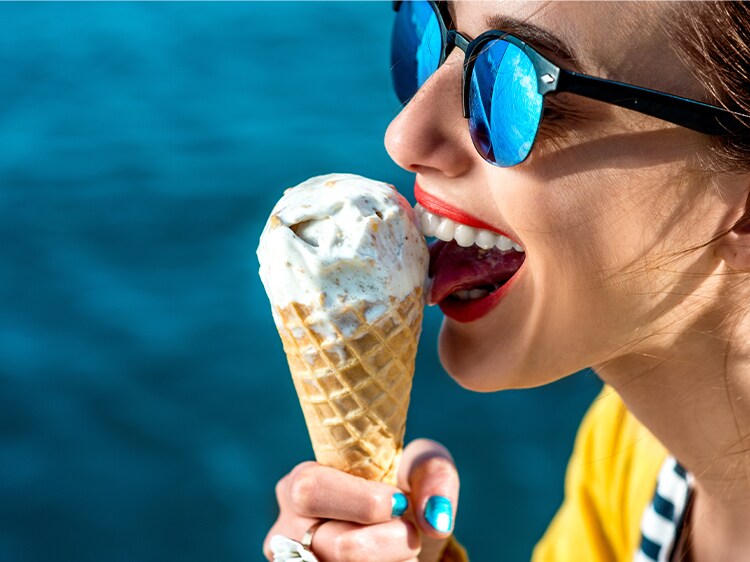 Kobieta nosząca okulary przeciwsłoneczne podczas jedzenia lodów.
