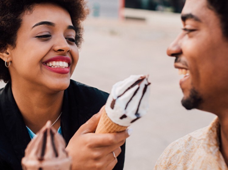 Kobieta i mężczyzna uśmiechający sie do siebie trzymając lody.