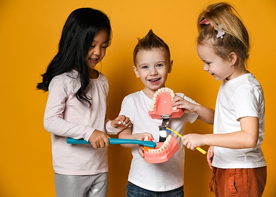 Trójka dzieci pokazująca na modelu jak szczotkuje się zęby
