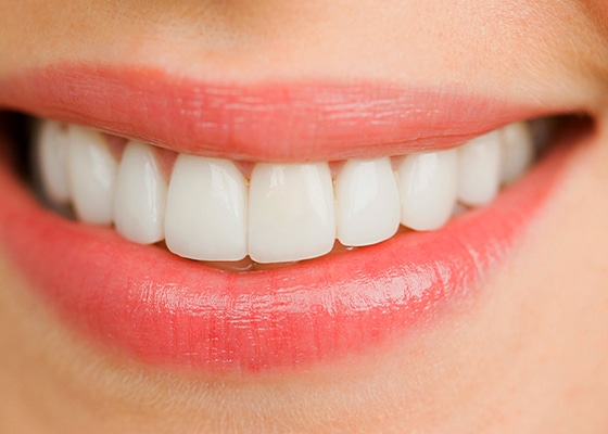 Zbliżenie na uśmiechniętą twarz pokazującą czyste, białe zęby.